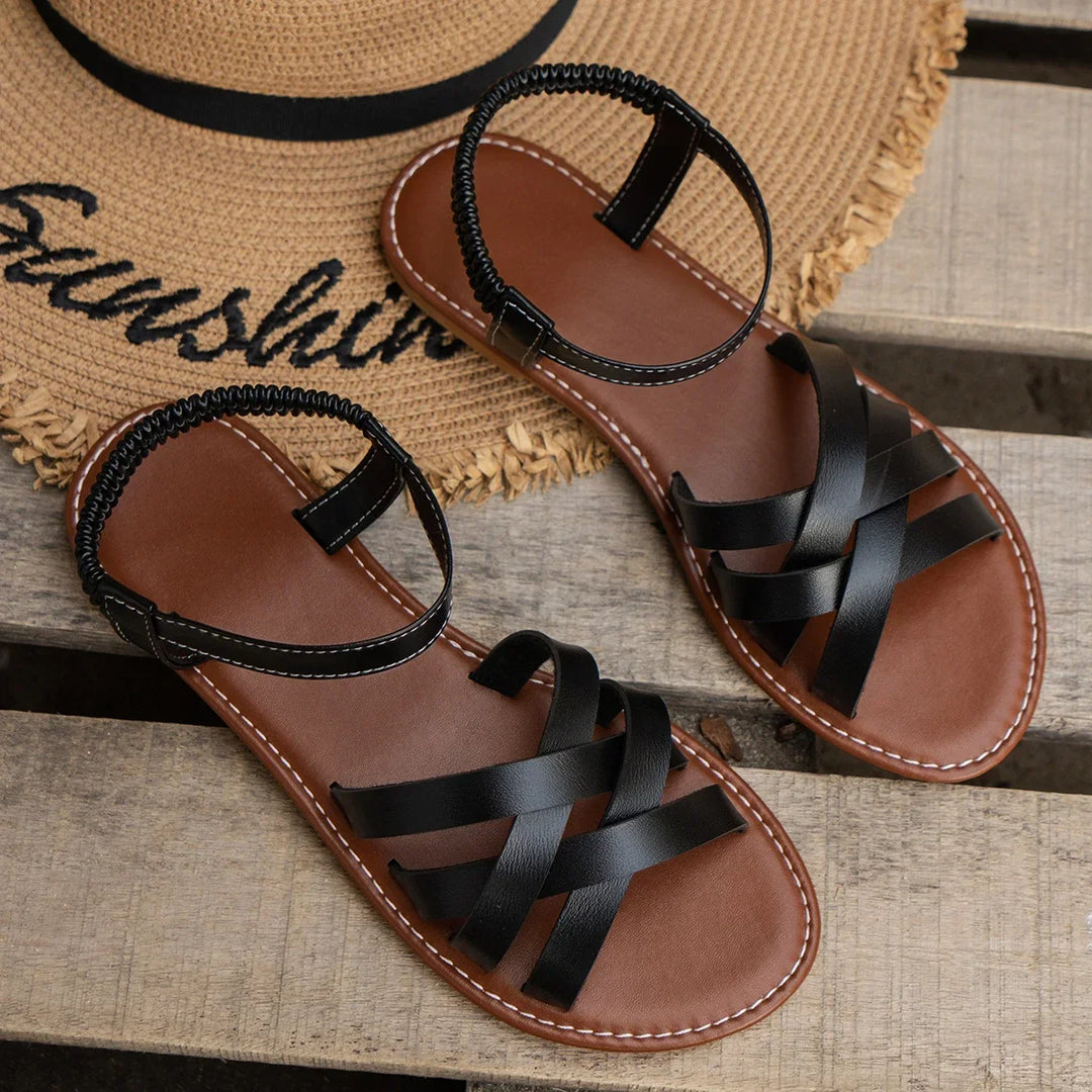 Women's strappy flat sandals in brown styled on neutral background showing full silhouette and strap detail