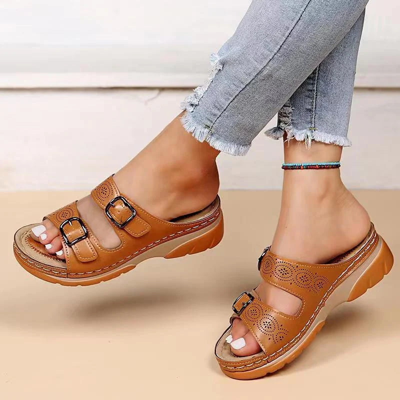 Close-up view of women's tan slide sandals featuring cushioned footbed and decorative perforations on upper straps