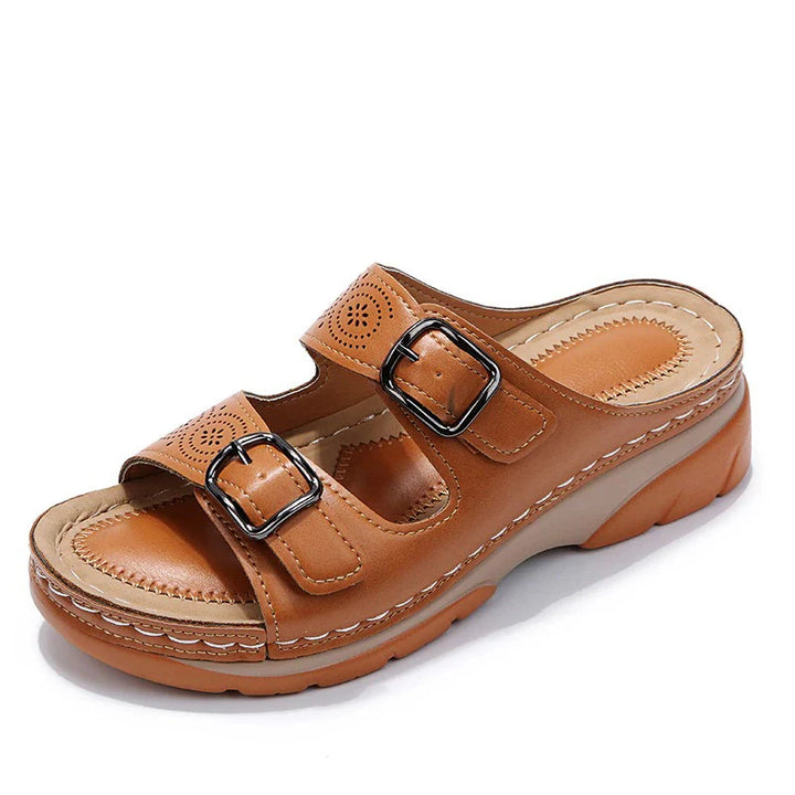 Women's tan slide sandals with cushioned insole and open-toe design paired with casual denim trousers