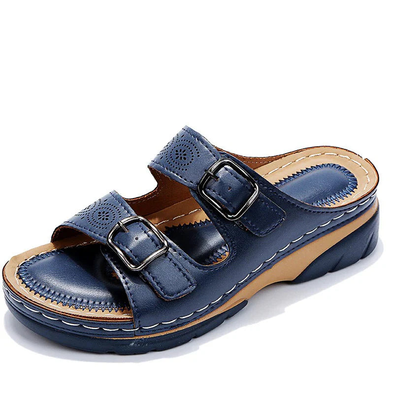 Detail shot of adjustable buckle closure on women's slide sandals with decorative perforations and stitching