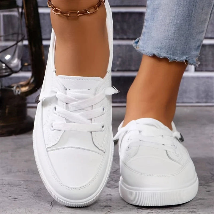 Close-up of women's white trainers showing smooth upper and adjustable lace-up closure
