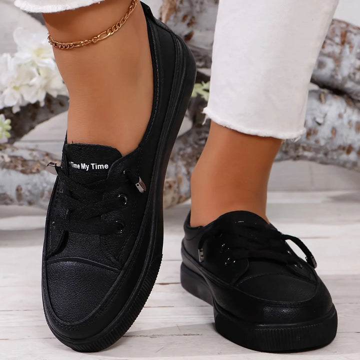 Women's white lace-up trainers on foot, displaying low-top silhouette and comfortable fit