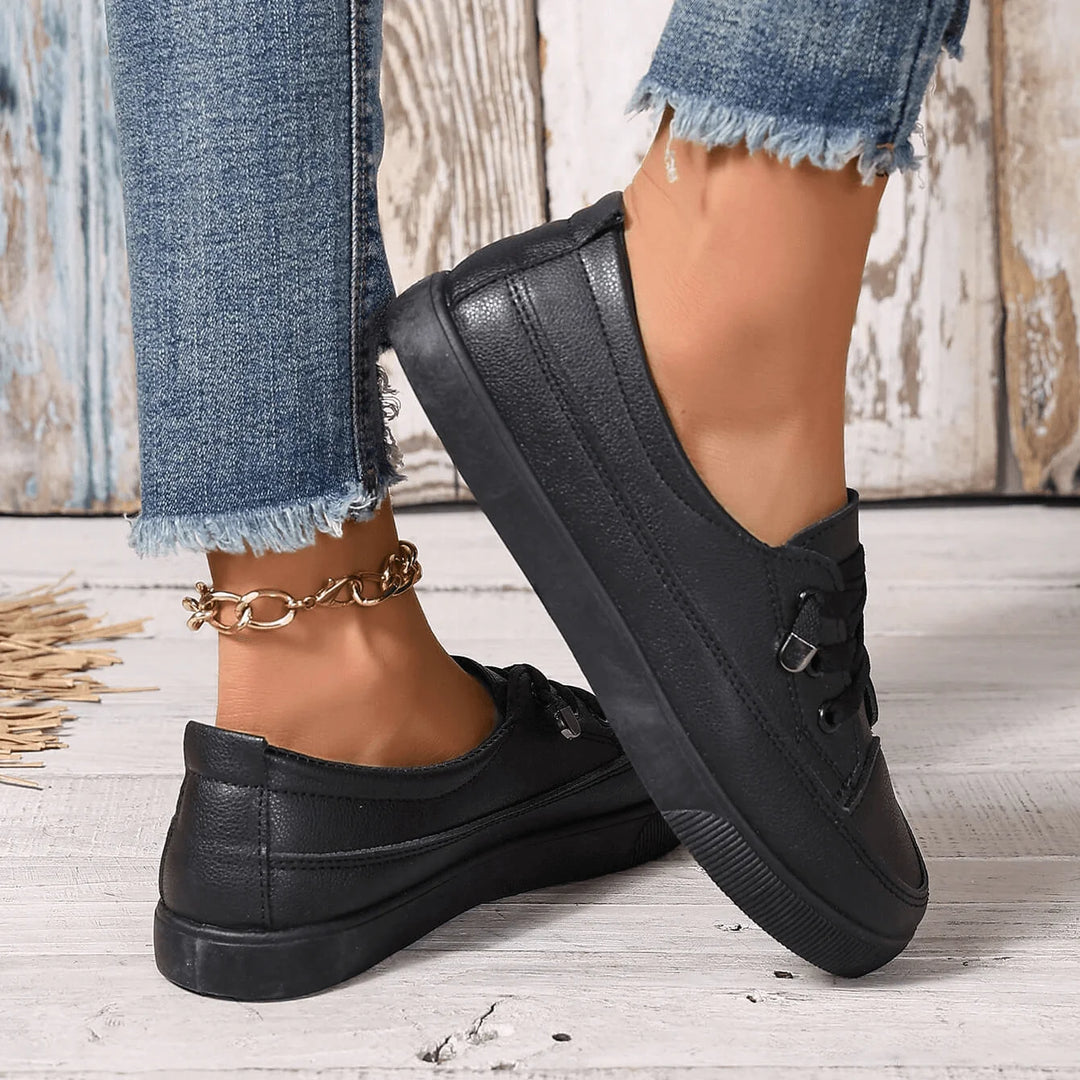 Women's white trainers with flat laces and smooth finish, paired with casual outfit
