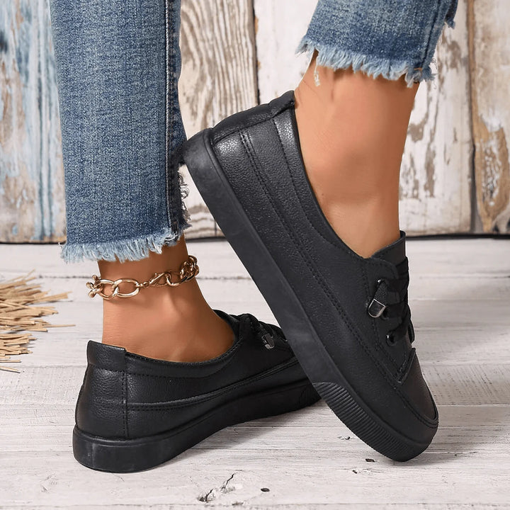 Women's white trainers with flat laces and smooth finish, paired with casual outfit