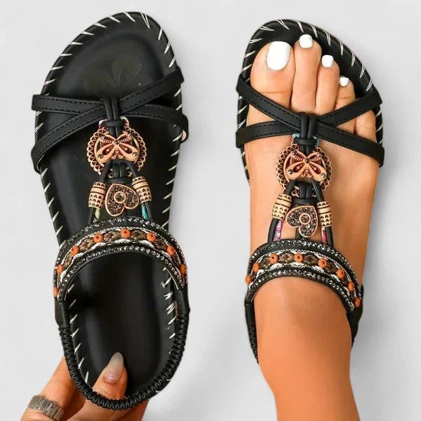 Close-up view of women's T-strap sandals showing decorative beaded embellishments and whipstitch edging detail