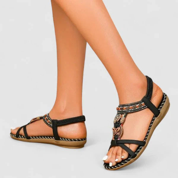 Close-up of women's sandals showing intricate beaded detailing across T-strap and toe post area