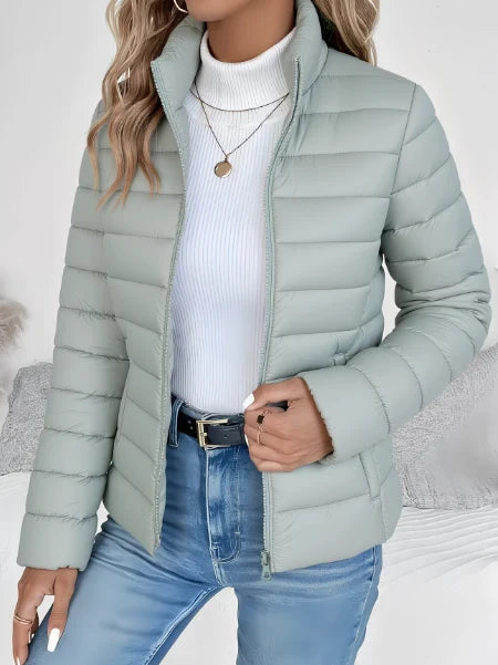 Woman wearing a mint green lightweight quilted spring jacket with high stand collar and full zip closure