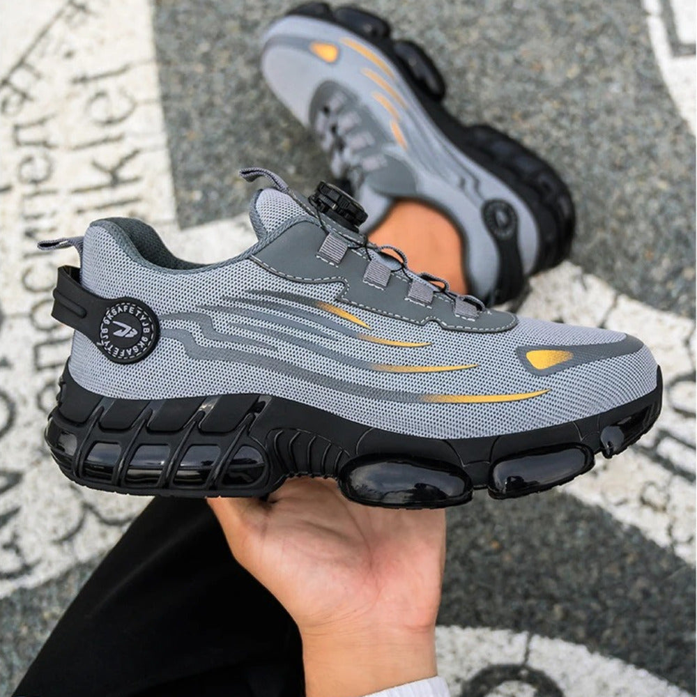 Grey safety trainer held in hand showing the grip sole