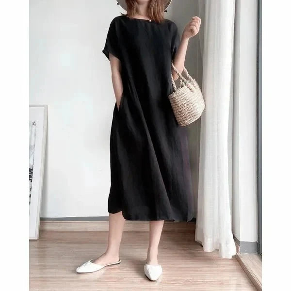 Rear view of linen short sleeve midi dress in black with relaxed straight silhouette and side pockets