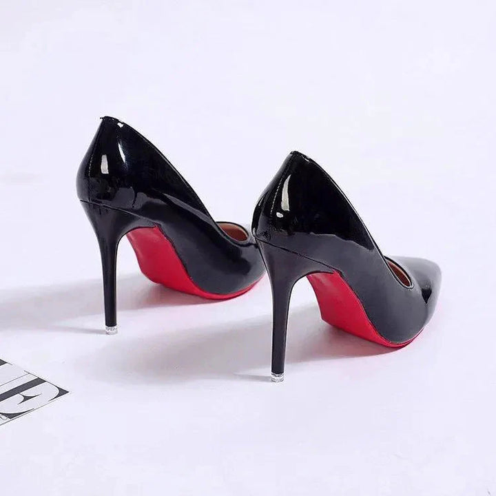 Pointed toe stiletto heels in black patent with model wearing sheer tights