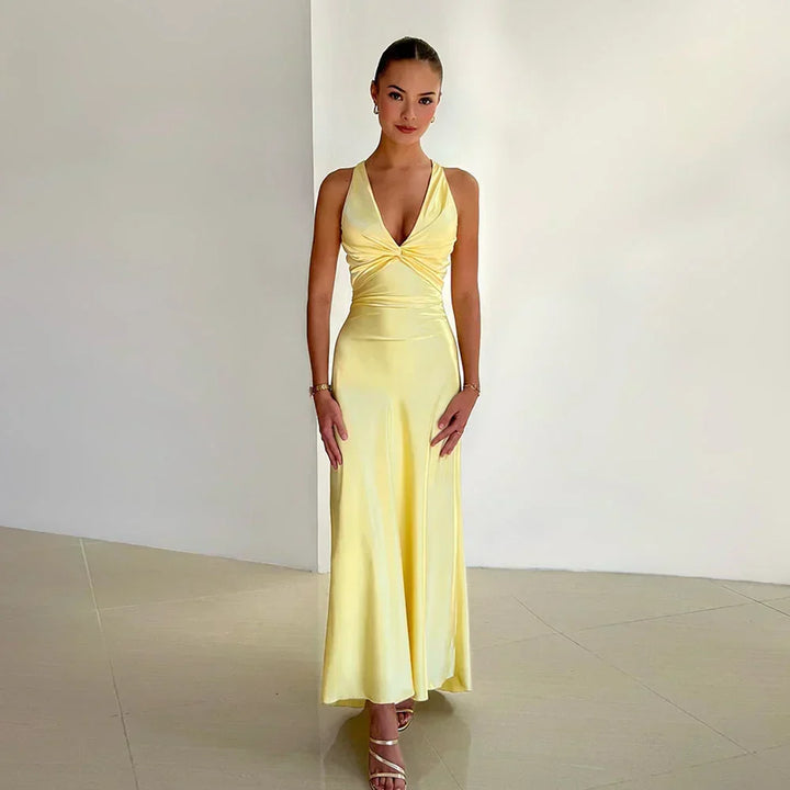 Woman wearing yellow crossover neckline wedding guest dress with draped bodice and maxi length skirt
