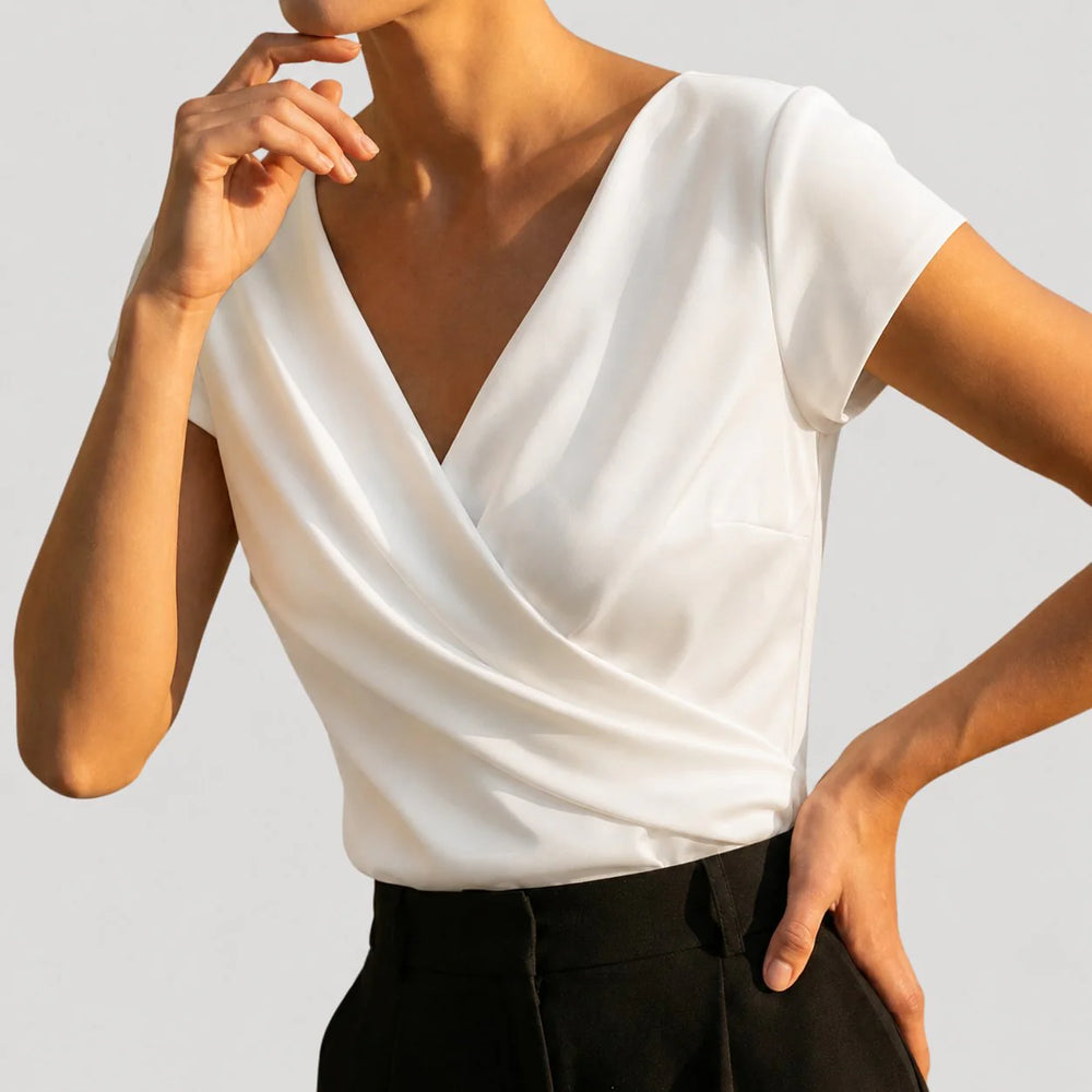 Close-up of draped wrap blouse showing v-neckline and soft crossover folds on bodice