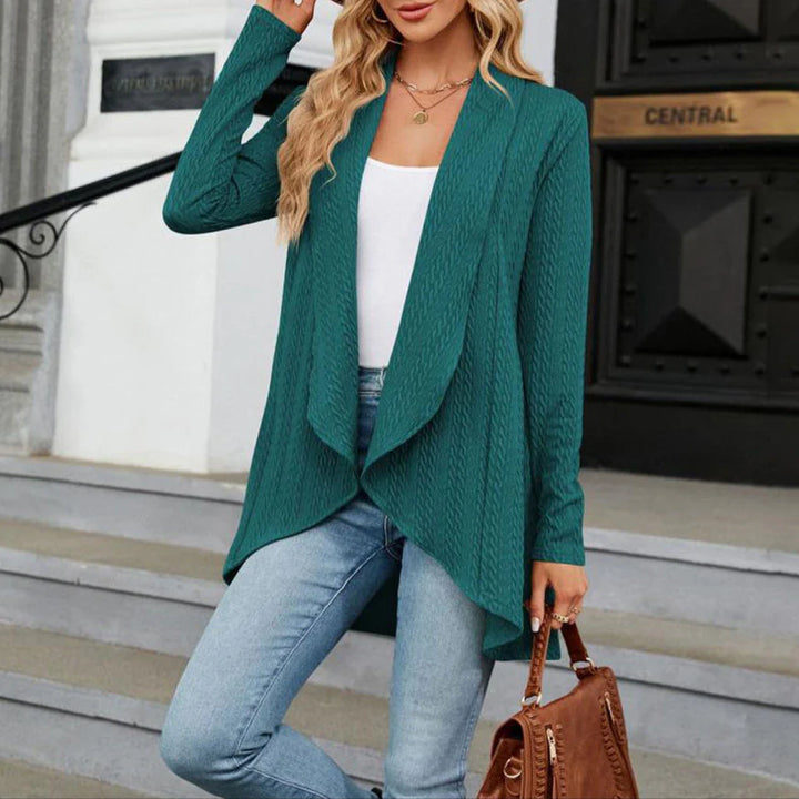 Teal open front cardigan with textured fabric and asymmetric hem worn over white top and jeans
