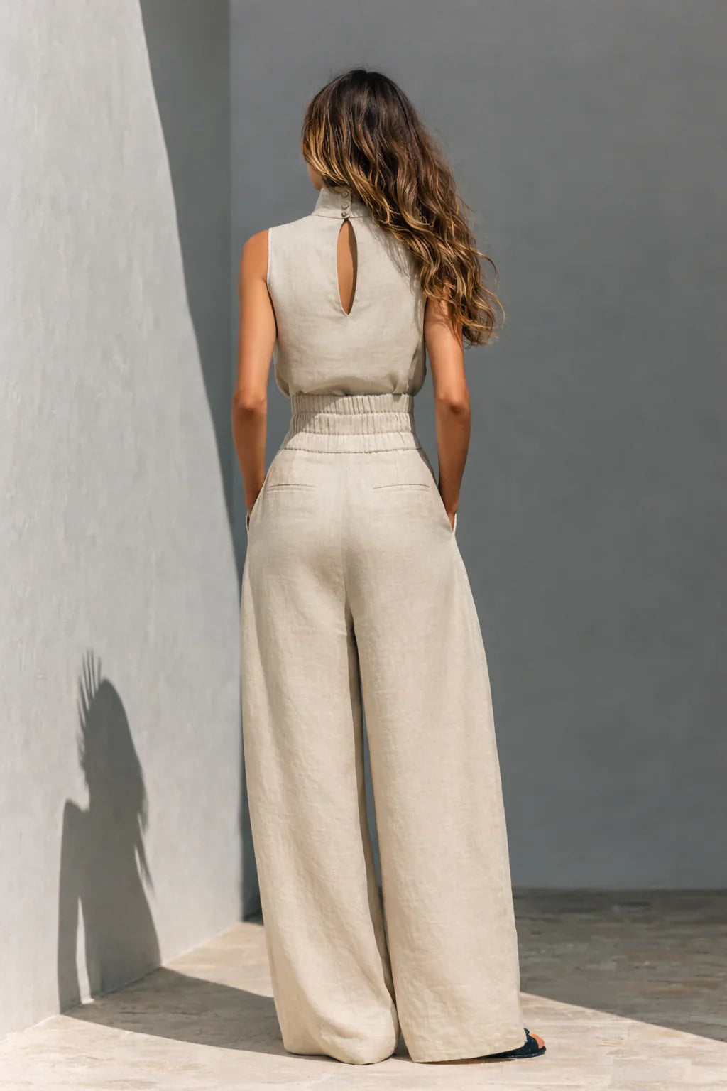 Sleeveless high neck top paired with wide leg pleated trousers in coordinated beige fabric