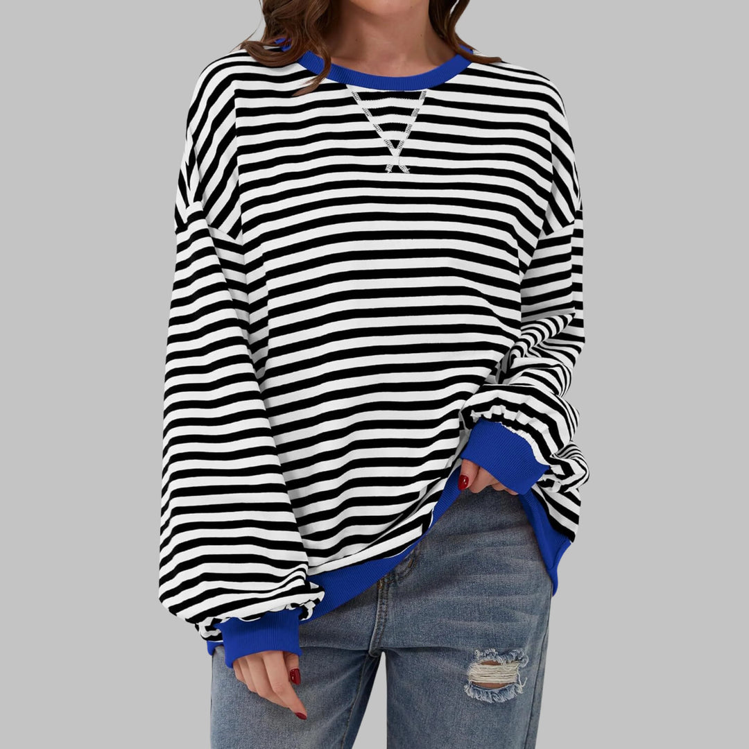 Model wearing green and navy striped sweatshirt paired with distressed denim jeans for casual styling