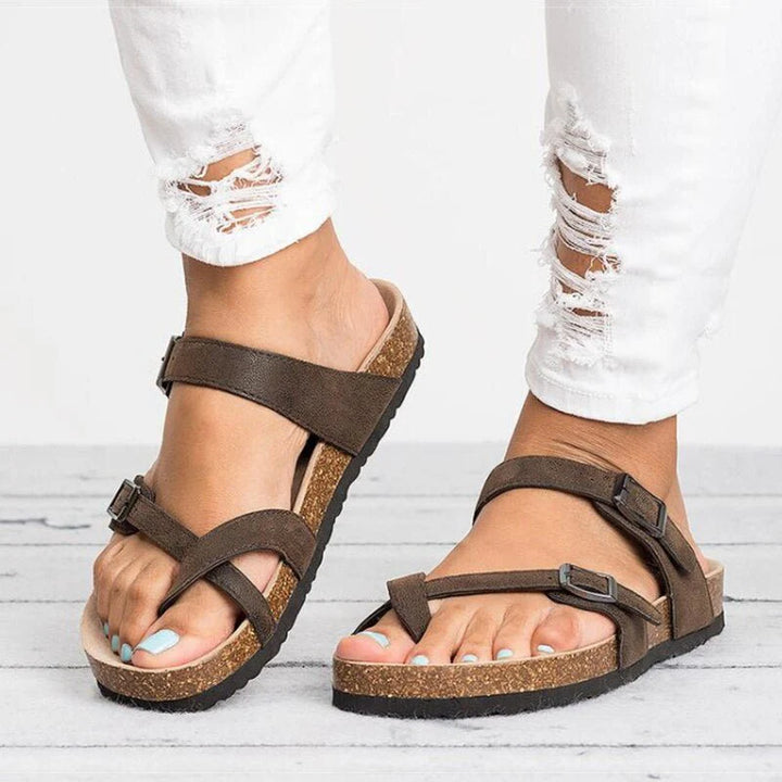 Close-up view of women's toe-post sandals showing adjustable buckle straps and textured cork footbed