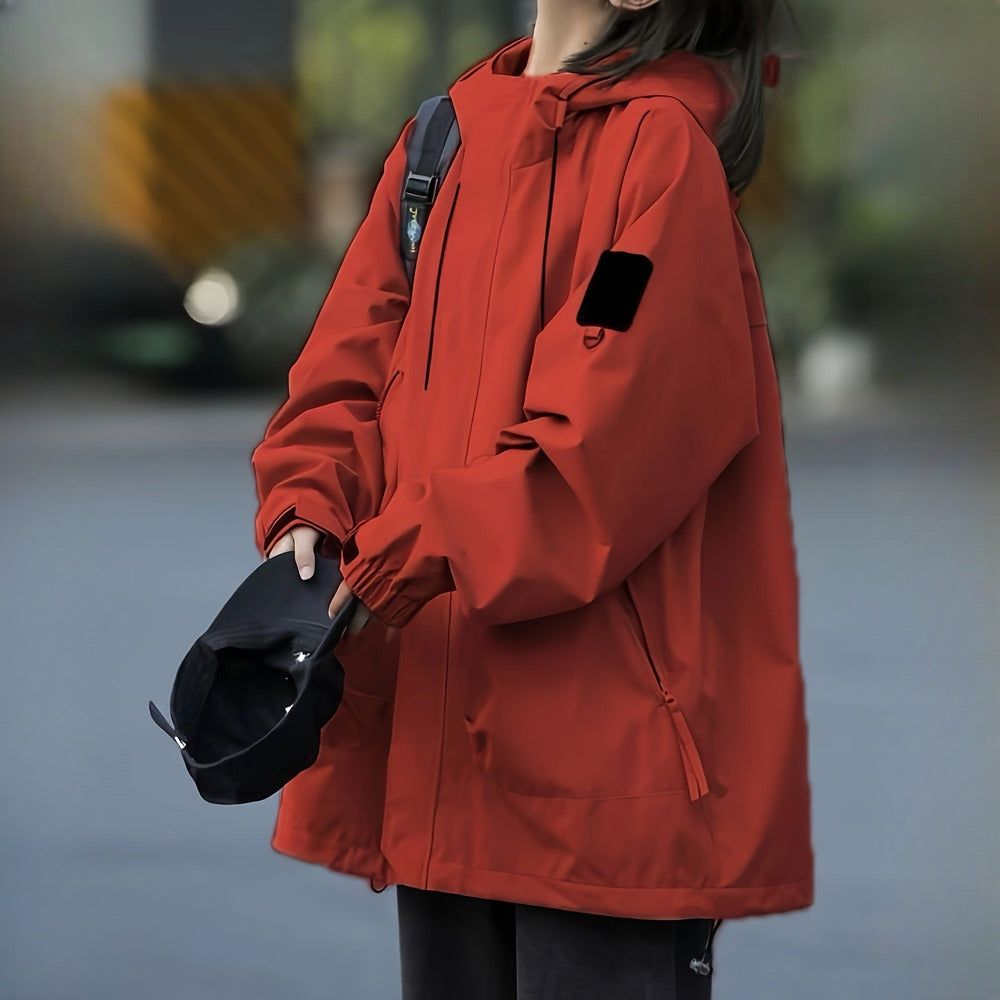 Women's windproof hooded mountain jacket in brick red, worn on model